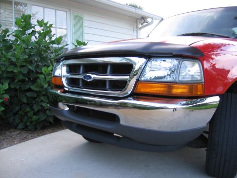 1974 Ford F-100 - Front view of a red Ford Ranger with a chrome grille and bumper, parked in front of a house.