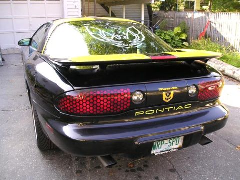 1984 Pontiac Fiero - Rear view of a black Pontiac Trans Am with yellow trim and distinctive honeycomb taillights.