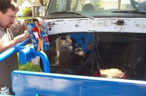 1979 Ford Bronco - Man holds a magazine in front of the open engine bay of a white truck.