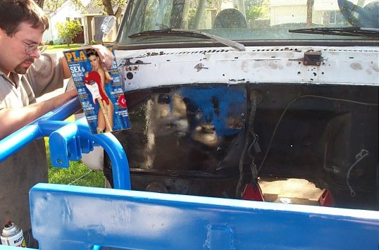 Man holding Playboy magazine in front of open engine bay of a white truck