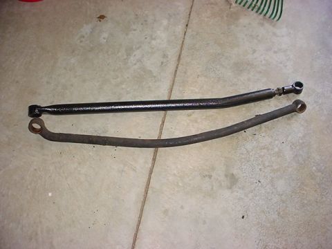 1979 Ford Bronco - Two steering linkage bars are shown on a concrete surface.