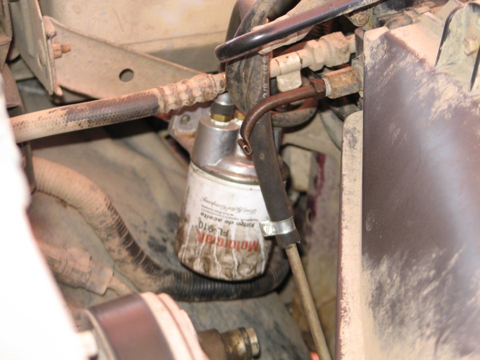 Motorcraft FL-910 oil filter mounted in a dusty engine bay with rusty lines and hoses