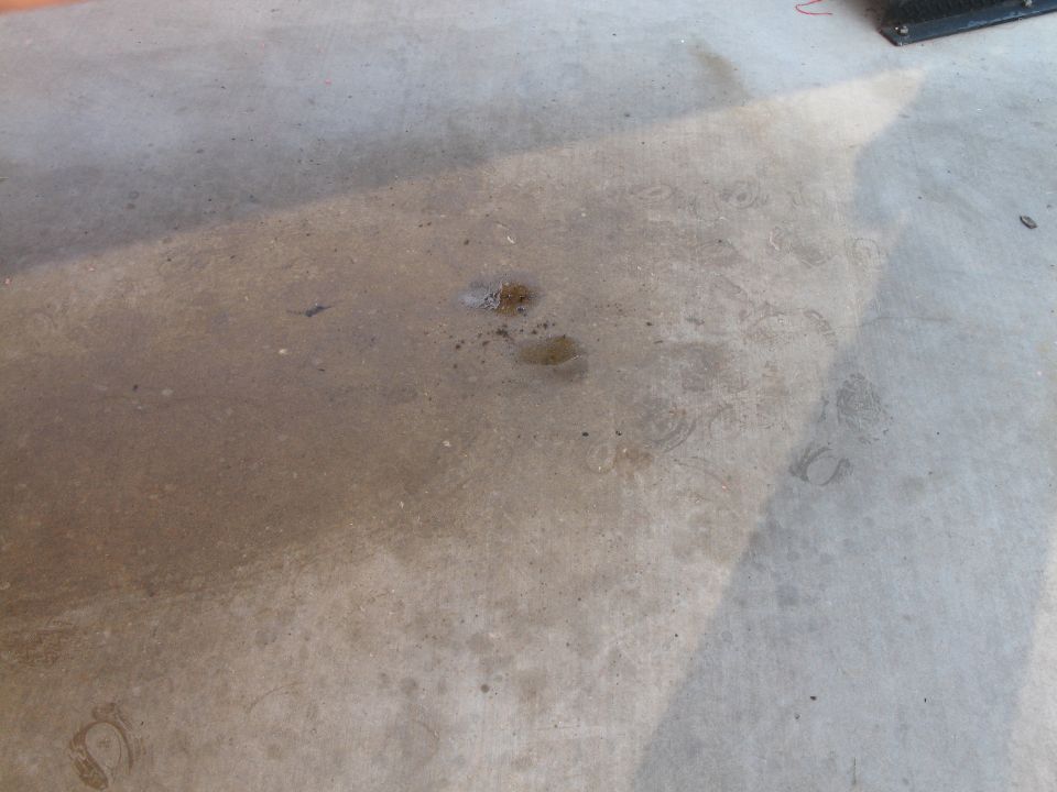 Concrete floor with dark fluid stains and faint tire marks
