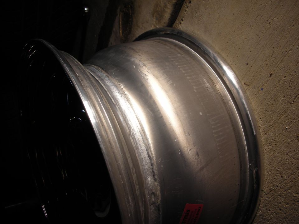 Side profile of a polished aluminum wheel barrel with a warning label