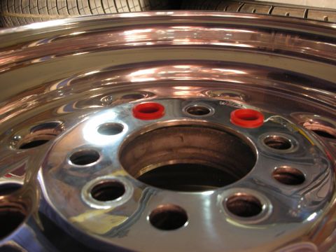 1998 Ford Crown Victoria - Close-up of a polished aluminum wheel center with red lug-hole accents, mounted with a tire visible behind it.