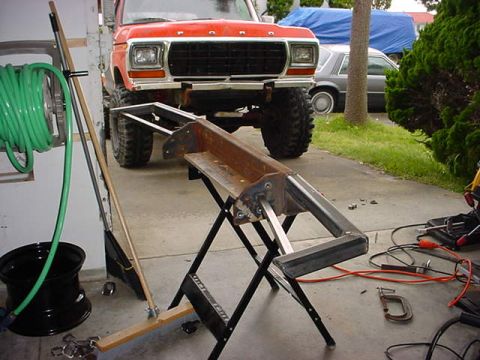 1979 Ford Bronco - A red 1979 Ford Bronco is parked in front of a garage, with a metal workbench and tools scattered around.