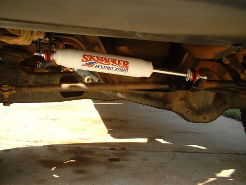 1995 Ford F-150 - A Skyjacker Hydro 7000 steering stabilizer is visible on the underside of a vehicle, attached to the steering linkage.
