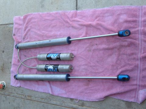 1985 Ford Bronco II - Four Fox shock absorbers are displayed on a pink towel, with visible branding on two of the smaller units.