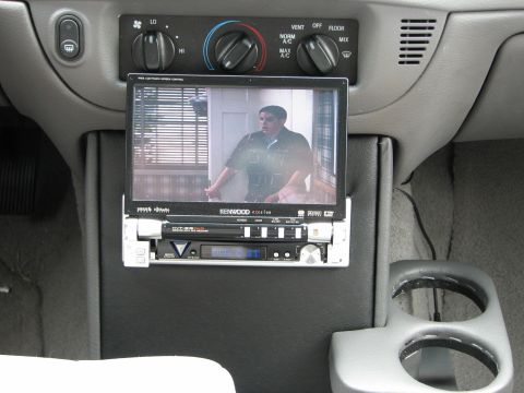 2002 Ford Crown Victoria - Aftermarket screen and stereo installed in a car's center console area, with cup holders visible.