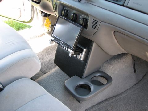 2002 Ford Crown Victoria - The interior of a car features an aftermarket stereo system installed in a custom console, with a dual cup holder nearby.