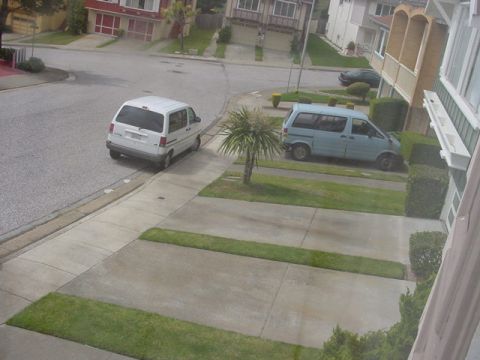 1979 Ford Bronco - Two minivans are parked on a suburban street and driveway, with houses visible in the background.