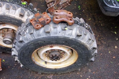 1978 Ford Bronco - Several old tires and rusty metal brackets are piled up outdoors.