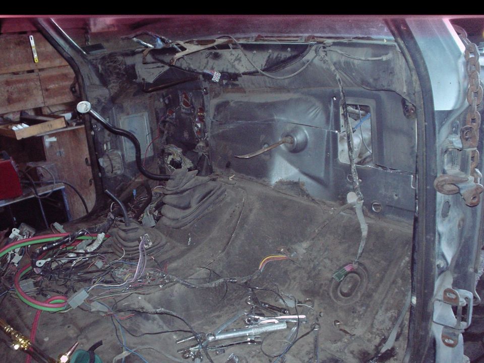 Gutted truck interior stripped to bare floor with loose wiring and tools