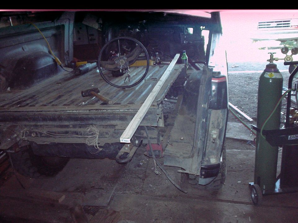 Rear of a 1980s Ford Bronco with its bed removed, showing exposed frame and wiring