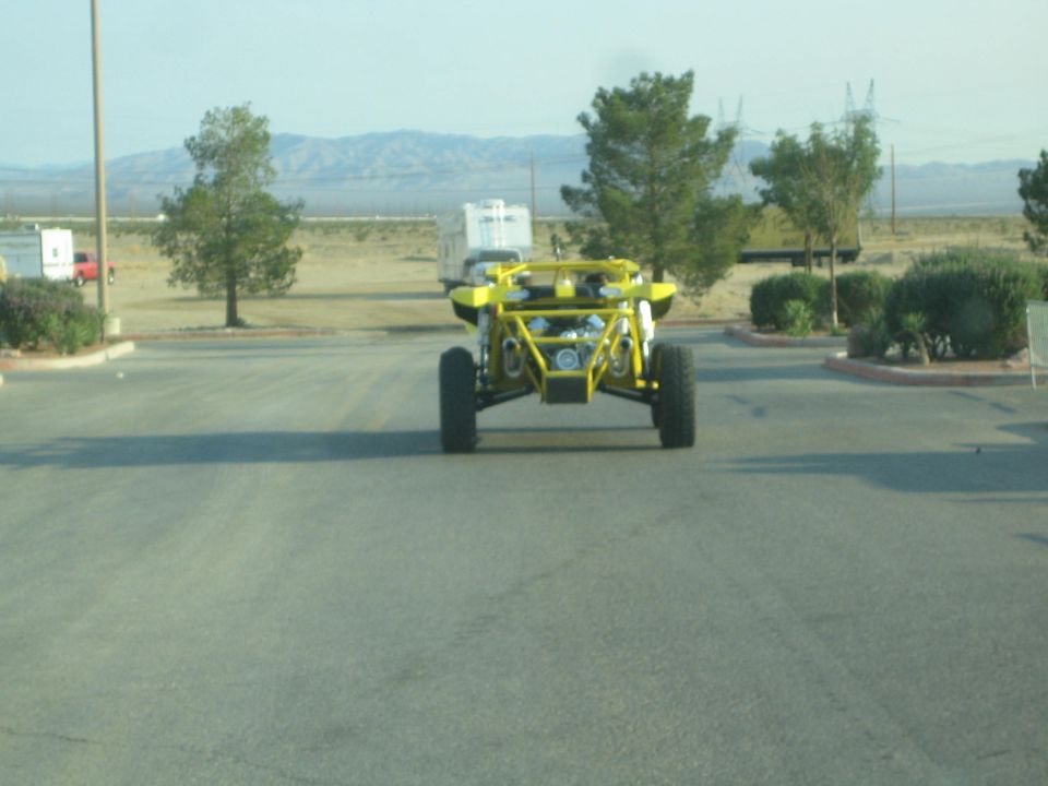 Yellow tube-frame sand rail buggy on a road with desert mountains behind