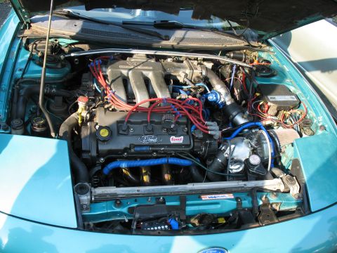 1997 Ford Probe - The engine bay of a 1997 Ford Probe shows a V6 engine with aftermarket modifications and colorful wiring.