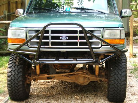 1996 Ford Bronco - Front view of a green Ford Bronco with a custom brush guard and off-road tires.