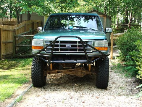 1996 Ford Bronco - Front view of a green 1996 Ford Bronco equipped with an aftermarket bull bar and off-road tires.