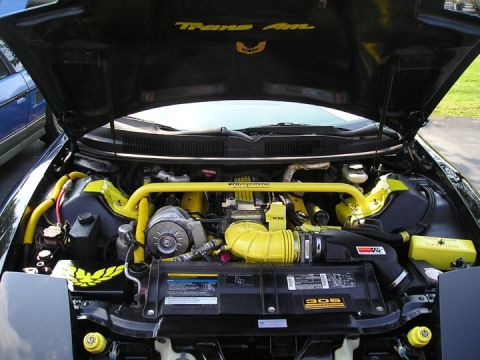 1984 Pontiac Fiero - The engine bay of a 1994 Pontiac Trans Am features yellow hoses, a strut bar, and custom air intake.