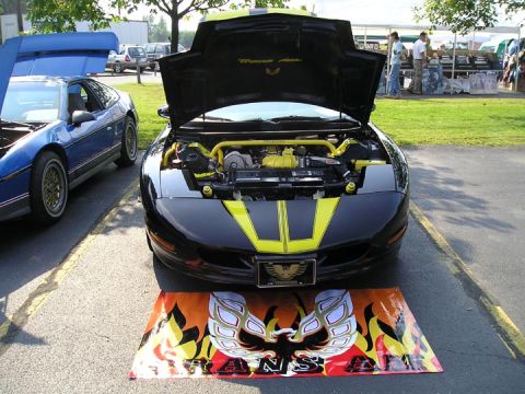1984 Pontiac Fiero - A black Pontiac Trans Am with its hood open is displayed next to a blue Pontiac Fiero.