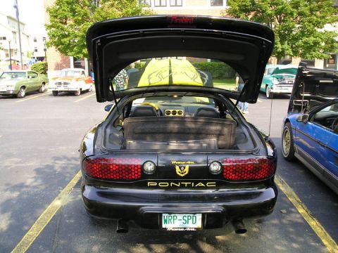 1984 Pontiac Fiero - This black 1994 Pontiac Trans Am is parked at an outdoor car show with its trunk open.