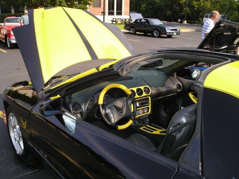 1984 Pontiac Fiero - Interior view of a black convertible with yellow accents and racing stripes on the hood, identified as a 1994 Pontiac Trans Am.