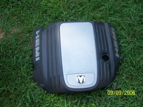 1979 Ford F-150 - Engine cover with "HEMI" and "5.7L V8" branding, the Dodge Ram emblem, resting on grass.