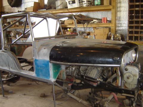 1992 Ford Bronco - A Jeep CJ-6 is undergoing modifications in a workshop, with a custom roll cage and exposed engine components visible.