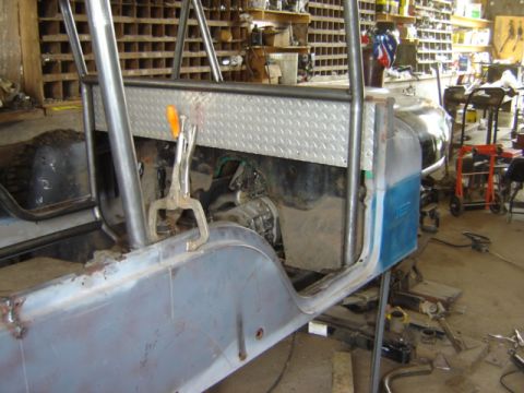 1992 Ford Bronco - The body of a Jeep CJ-6 is seen in a workshop, a diamond plate panel and roll cage tubing, indicating ongoing restoration work.