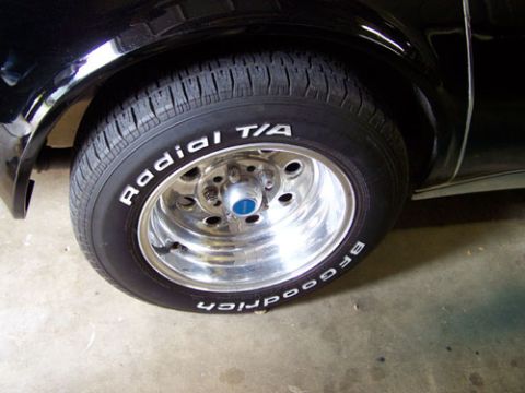 1975 Chevrolet Corvette - A close-up shot focuses on the tire and chrome wheel of a black vehicle.