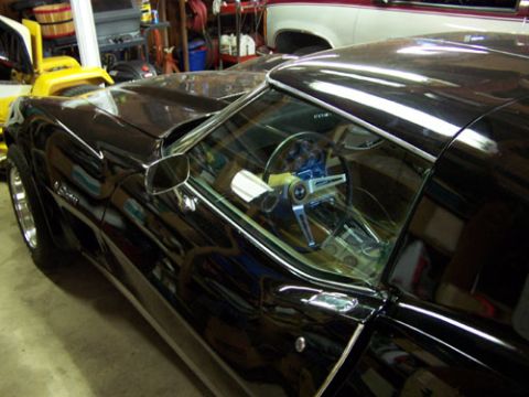 1975 Chevrolet Corvette - Side view of a black 1975 Chevrolet Corvette, showing the interior and a custom steering wheel.