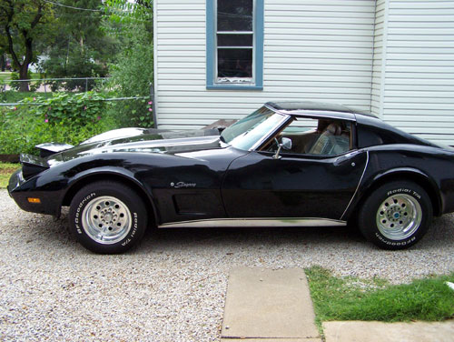 Black C3 Chevrolet Corvette Stingray coupe side view on a gravel driveway