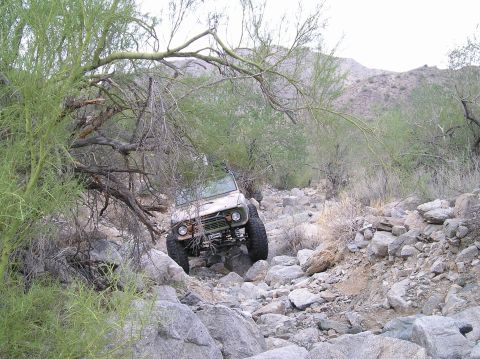 1993 Ford Bronco - Vehicle is driving through a very rocky and uneven terrain in a desert environment.