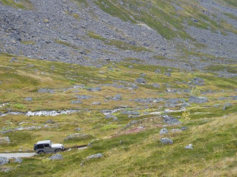 2000 Ford E350 - A Jeep navigates a rough terrain with a stream and rocky slopes in the background.
