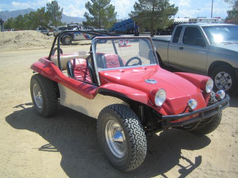 1990 Ford Bronco - red Meyers Manx-style fiberglass dune buggy with red interior and roll bar parked on a dusty lot near pine trees.