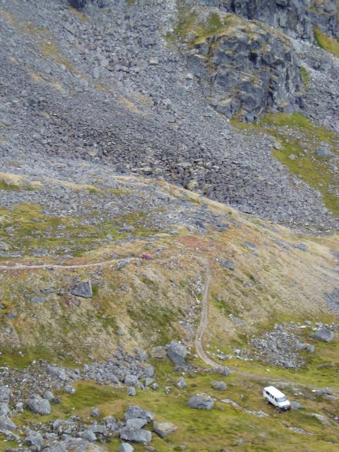 2000 Ford E350 - Two vehicles navigate a narrow dirt track on a steep, rocky mountain slope.