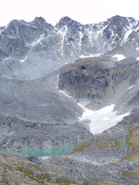 2000 Ford E350 - A remote mountain lake is surrounded by , rocky slopes with patches of snow.