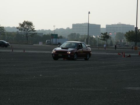 2001 Mercury Grand Marquis - A red sedan with racing numbers navigates a course marked by orange cones on a hazy day.