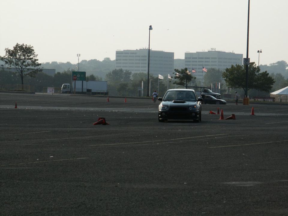 Front view of a black Subaru WRX STI on a track with cones. Another car is behind it