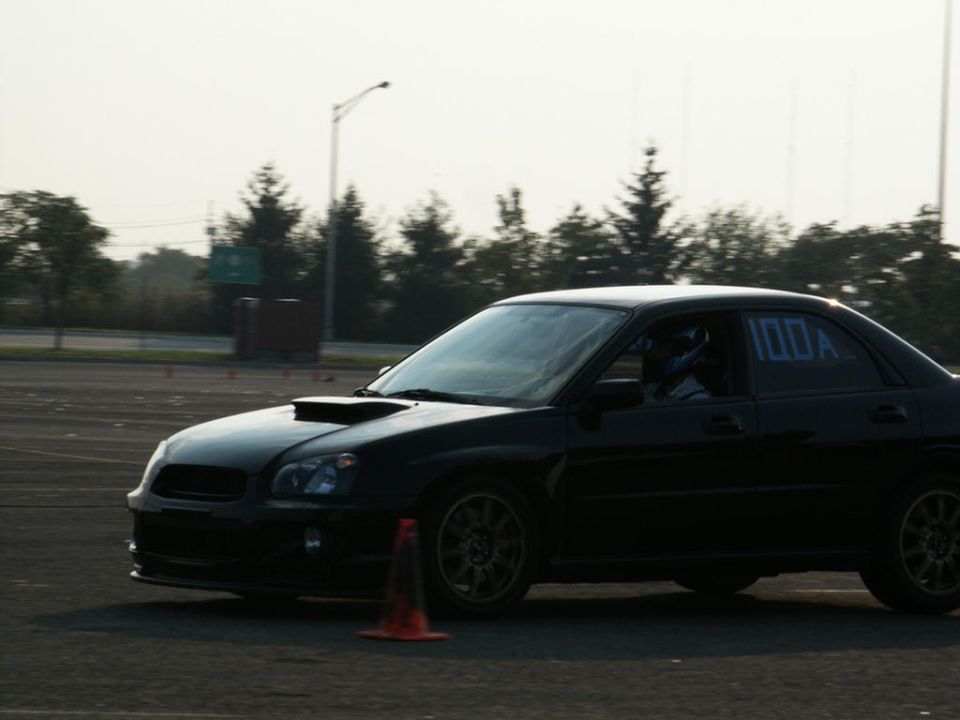 Black Subaru Impreza WRX with hood scoop and racing numbers on window