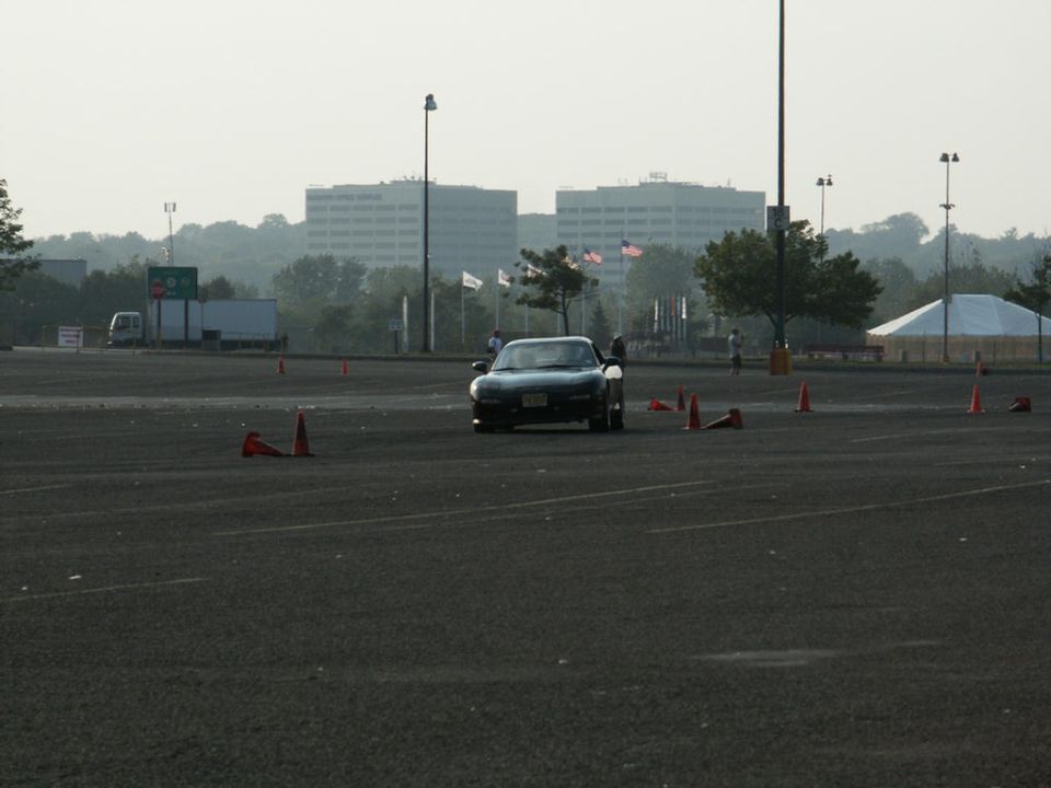 Black Mazda Miata driving through cones in a parking lot