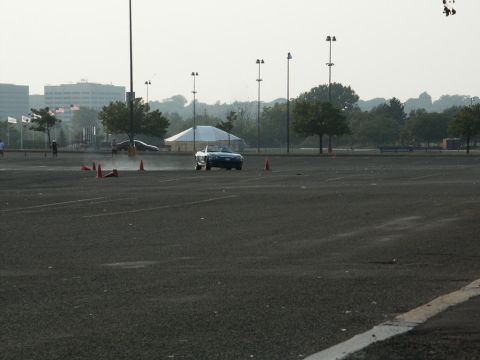 2001 Mercury Grand Marquis - A blue convertible sports car navigates a cone course in an open lot with buildings in the background.