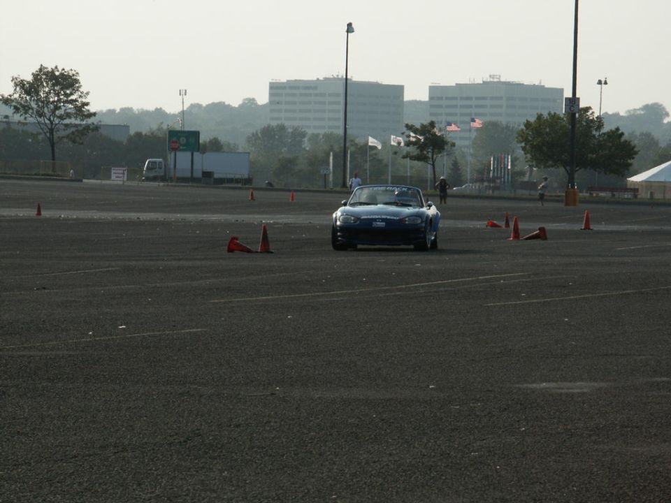 Blue convertible sports car on a paved lot with cones