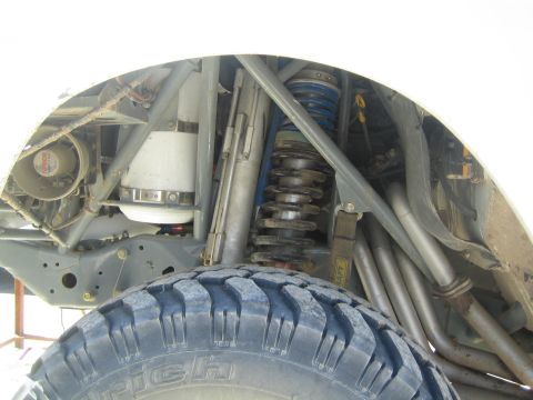 1990 Ford Bronco - Underside view of an off-road vehicle's front suspension showing coil springs, tubular links and a BFGoodrich tire.
