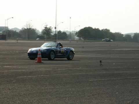 2001 Mercury Grand Marquis - A blue convertible sports car navigates a track marked with cones, with another vehicle visible in the distance.