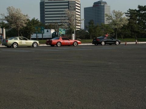 2001 Mercury Grand Marquis - Three cars are parked in a lot with buildings and trees in the background.
