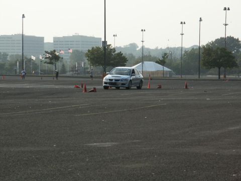 2001 Mercury Grand Marquis - Silver sedan on an asphalt course with cones and distant buildings.