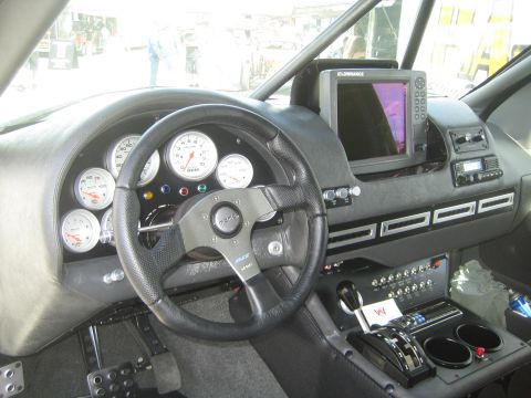1990 Ford Bronco - race vehicle cockpit showing a multi-gauge cluster, Lowrance GPS screen, steering wheel and floor shifter.