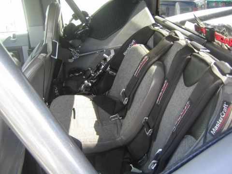 1990 Ford Bronco - interior of a race vehicle fitted with two gray MasterCraft seats and racing harnesses behind a roll cage.