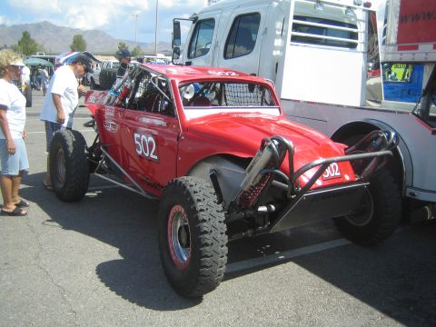 1990 Ford Bronco - red tube-chassis off-road race buggy numbered 502 sits on pavement as a few spectators stand beside it.